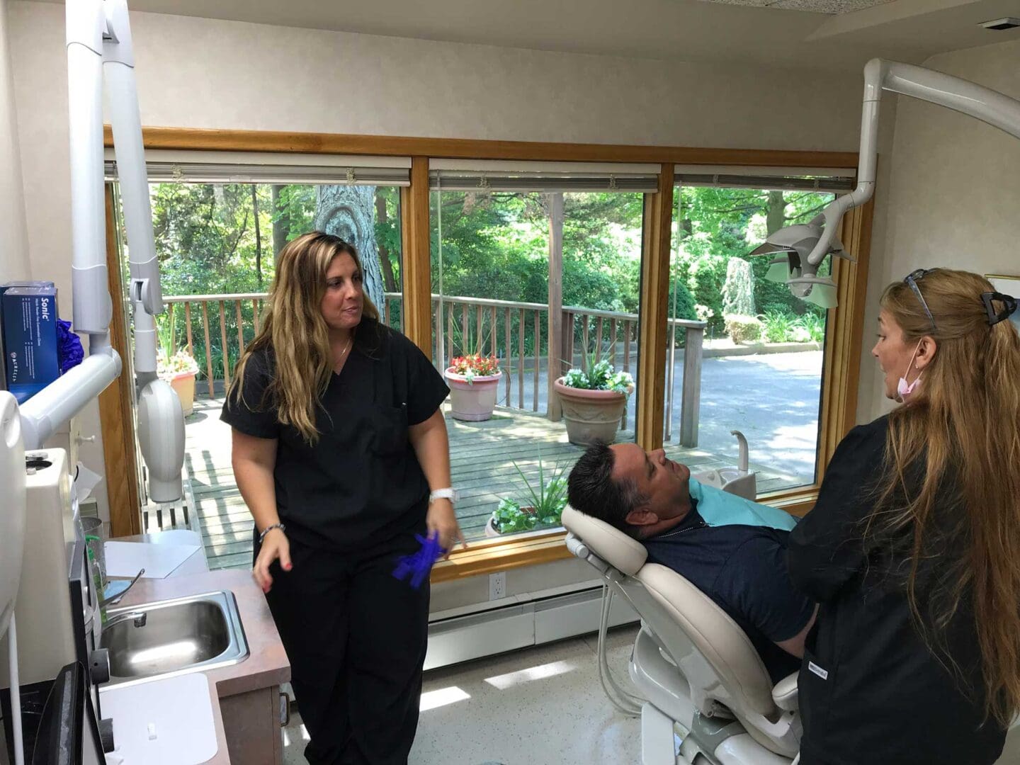 A dentist and his assistant are standing in front of the patient.